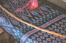 to Jpeg 50 K 9809P10 Three colour ikat on the loom at a weaving mill at Innbawkon (Inpawkhon) on Lake Inle, Shan State. Note the 'bow' across the width of the weft to keep the width and tension constant.