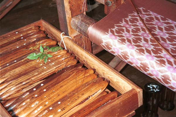 Jpeg 51K 9809P12 Width of 3 colour ikat silk weaving with a container of weft shuttles carefully in order for the ikat pattern at a weaving mill at Innbawkon (Inpawkhon) on Lake Inle, Shan State. 