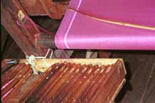 to Jpeg 39K 9809P13 Width plain silk weaving in between lengths of ikat with a container of weft shuttles carefully in order for the ikat pattern sections. All at a weaving mill at Innbawkon (Inpawkhon) on Lake Inle, Shan State.