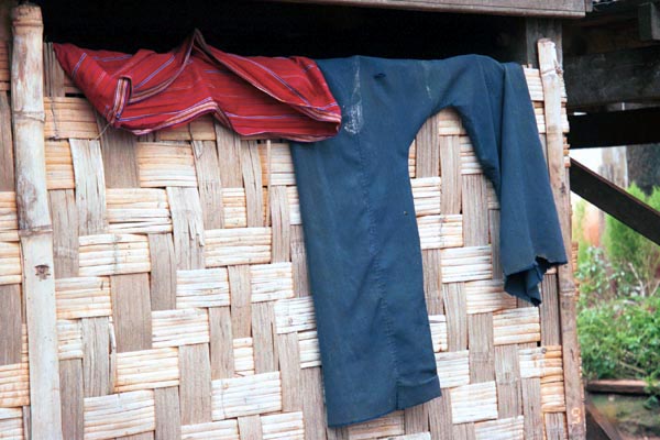 69K Jpeg A hand woven Silver Palaung woman's tube skirt and a man's trousers hanging over a woven split bamboo wall under a house in Pein Ne Bin village near Kalaw, southwestern Shan state.