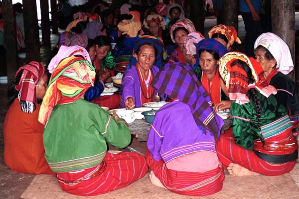 81K Jpeg Silver Palaung women eating the communal meal at the 'Full Moon day' festival in Pein Ne Bin village near Kalaw, southwestern Shan State. Note their traditional hand woven tube skirts, embroidered jackets, turbans and the bamboo rattan hoops around the waist, particularly of the woman on the right of the photo.