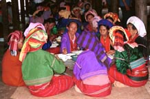 to 81K Jpeg Silver Palaung women eating the communal meal at the 'Full Moon day' festival in Pein Ne Bin village near Kalaw, southwestern Shan State. Note their traditional hand woven tube skirts, embroidered jackets, turbans and the bamboo rattan hoops around the waist, particularly of the woman on the right of the photo.