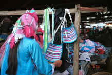Jpeg 37K Side comb Miao woman looking at back aprons which, aside from their decorative appearance act as a protective pad underneath a bottom of a carrying basket - De Wo market, De Wo township, Longlin county, Guangxi province 0010g27.jpg