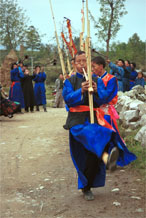to Jpeg 55K 0110D20  Villagers welcoming us to Gan He village, Ya Rong township, Huishui county, Guizhou province, south-west China. Musicians led by men playing on large lusheng pipes and followed by men blowing on very long (and loud) trumpets. The people living in this village are known as Qing Miao. There has been much intermarriage between Miao and Bouyei which is evident from the costume of the women. 