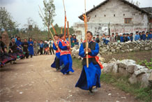 to Jpeg 52K  0110D25 Villagers welcoming us to Gan He village, Ya Rong township, Huishui county, Guizhou province, south-west China. Musicians led by men playing on large lusheng pipes. The people living in this village are known as Qing Miao. There has been much intermarriage between Miao and Bouyei which is evident from the costume of the women. 