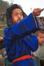 to Jpeg 51K  0110D29 Trumpeter blowing his welcome at Gan He village, Ya Rong township, Huishui county, Guizhou province, south-west China. Note the complex weaving of the ends of the head-cloth. These long trumpets are very loud! The people living in this village are known as Qing Miao.