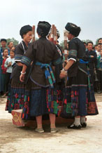 to Jpeg 56K  0110D33 Women beating sticky rice as part of a dance programme in Gan He village, Ya Rong township, Huishui county, Guizhou province, south-west China. The people living in this village are known as Qing Miao. There has been much intermarriage between Miao and Bouyei which is evident from the every-day costume of the women. The pieced skirts of applique and wax-resist being worn by the girls were originally only worn at funerals but today they are worn for special festivals and dance competitions. Note the bands of complex weaving on the sleeves of the women's jackets.
