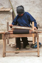 to Jpeg 51K 0110E03  Woman working on some complex weaving on a backstrap loom in Gan He village, Ya Rong township, Huishui county, Guizhou province, south-west China. The weaving will be cut into pieces to insert into the sleeves of women's jackets and to use on the ornamental ends of men's head-cloths. The people living in this village are known as Qing Miao. There has been considerable intermarriage between Miao and Bouyei and the costume is very mixed. 