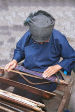 to Jpeg 53K 0110E08  Woman working on some complex weaving on a backstrap loom in Gan He village, Ya Rong township, Huishui county, Guizhou province, south-west China. The weaving will be cut into pieces to insert into the sleeves of women's jackets and to use on the ornamental ends of men's head-cloths. The people living in this village are known as Qing Miao. There has been considerable intermarriage between Miao and Bouyei and the costume is very mixed. 