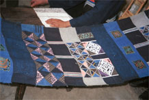 to Jpeg 57K  0110E22 A length of pieced fabric ready to be made up into a skirt. Note the wax resist in two shades of indigo, embroidered work and applied plaid triangles of cloth, Gan He village, Ya Rong township, Huishui county, Guizhou province. This is a Qing Miao (or Bouyei/Miao as there has been much intermarriage and the costume is very mixed). 