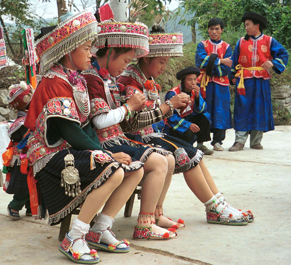 Jpeg 138K Iron beating Miao women in Gao Zhai village, Bai Jin township, Huishui county, Guizhou province working on some embroidery and wearing their festival finery watched by the musicians 0110C28