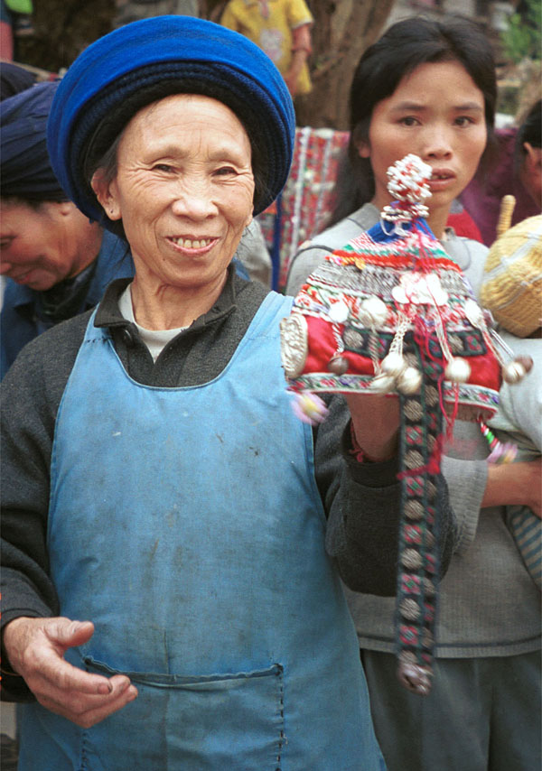 Jpeg 129K Iron beating Miao woman holding the girl's finely pleated hat which I have just bought in Gao Zhai village, Bai Jin township, Huishui county, Guizhou province 0110D08