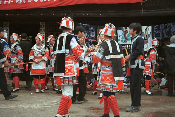 Jpeg 55K 0111G05 Gejia dance troupe performing in Ma Tang village, Kaili City, Guizhou province in November 2001. The apparently wax resist fabric in their costume - at least the headdress, apron and sleeves of the blouse - are now generally made from commercially printed fabric which imitates the Gejia traditional wax resist designs. 