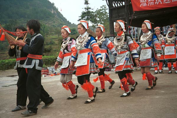 Jpeg 56K 0111G12  Gejia dance troupe performing in Ma Tang village, Kaili City, Guizhou province in November 2001. The apparently wax resist fabric in their costume - at least the headdress, apron and sleeves of the blouse - are now generally made from commercially printed fabric which imitates the Gejia traditional wax resist designs.
