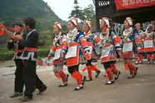 to Jpeg 56K 0111G12  Gejia dance troupe performing in Ma Tang village, Kaili City, Guizhou province in November 2001. The apparently wax resist fabric in their costume - at least the headdress, apron and sleeves of the blouse - are now generally made from commercially printed fabric which imitates the Gejia traditional wax resist designs.