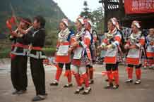 to Jpeg 56K 0111G14 Gejia dance troupe performing in Ma Tang village, Kaili City, Guizhou province in November 2001. The apparently wax resist fabric in their costume - at least the headdress, apron and sleeves of the blouse - are now generally made from commercially printed fabric which imitates the Gejia traditional wax resist designs. 