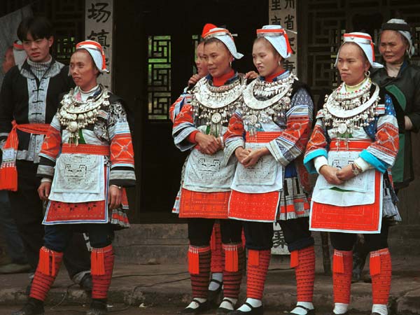 Jpeg 56K 0111G17 Gejia dance troupe performing in Ma Tang village, Kaili City, Guizhou province in November 2001. The apparently wax resist fabric in their costume - at least the headdress, apron and sleeves of the blouse - are now generally made from commercially printed fabric which imitates the Gejia traditional wax resist designs. 