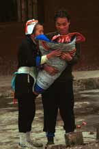 to Jpeg 53K 0111G28 A Gejia couple loving their baby which is wrapped in a winter wax resist baby carrier. Ma Tang village, Kaili City, Guizhou province.