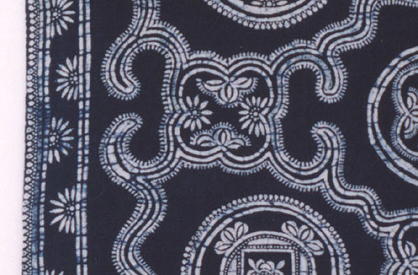 Jpeg 61K detail 42 ej2 In order to illustrate the skill required to create fine batik, Andrew has shown us five examples from his collection of what can go wrong when making batik jackets. (Shown as line four of the jackets in the photogallery.) This jacket illustrates what happens if the cloth is folded or crumpled too much after waxing but before dying. The wax will crack, allowing the dye to penetrate into the cloth, leaving the thin blue lines across the pattern (called “ice lines”), and/or, areas of wax will be loosened, giving a blurred and indistinct white pattern.