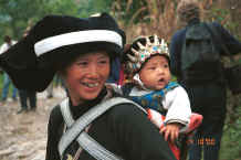 Jpeg 31K Side comb Miao woman and baby showing the baby's hat sporting protective white metal Buddhas - Long Dong village, De Wo township, Longlin country, Guangxi province 0010d32.jpg