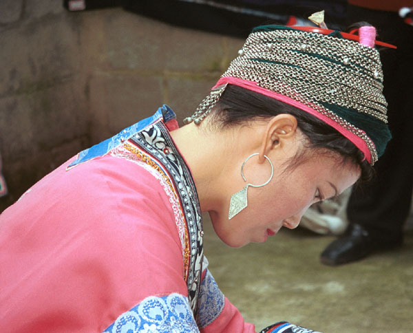 Jpeg 75K Miao woman concentrating on her wax resist. Note her traditional hair style (and a la dio (wax knife) tucked in her hair near the circular (red) comb. Lou Jia Zhuang village, Anshun city, Guizhou province 0110B21
