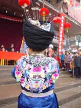to Jpeg 48K Back view of a Miao girl at a festival in a village in Songtao Miao Autonomous County, Tongren Prefecture, eastern Guizhou Province. Note the silver decorations peeping out of the headdress and the bold embroidery collar covering the back of the blouse.