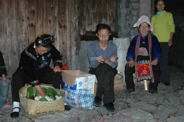 63K Jpg image Female villagers giving a little money, rice, eggs and so on. They receive steamed sticky rice and a meal.