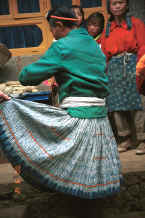 Jpeg 43K Big Flower Miao woman showing her skirt where the pattern has been created by indigo dye and stitch resist rather than batik as has the apron on the woman in the background.  This stitch resist is preferred over batik for work clothes as the women said that it was more hard wearing - it probably takes longer to do the batik wax resist which would be another reason for keeping it for more special occasions.  Xian Ma village, Hou Chang township, Puding county, Guizhou province 0010y05.jpg
