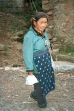 Jpeg 28K Side Comb Miao woman walking through a village beside the road - after leaving Hou Chang township for Puding, Guizhou 0010z06.jpg