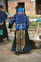 Jpeg 38K Back view of Black Miao woman wearing her festival finery kneading festival sticky rice, Zuo Qi village, Min Gu township, Zhenfeng county, Guizhou province 0010q05.jpg