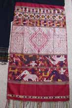to Silk supplementary weft end of a pha biang showing siho, mythological animals half-lion, half-elephant, unique to the Lao culture, with spirit figures on their backs walking amongst other figures including nak