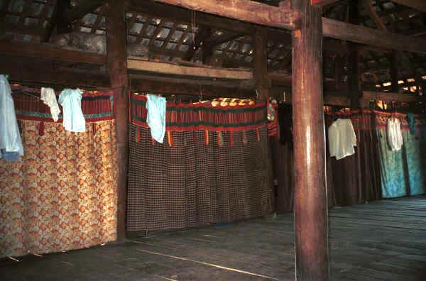 Jpeg 34K Curtains separating off the sleeping areas from each other and from the living area in a Black Thai (Tai Dam) House.in Dien Bien Phu, Lai Chau Province, Vietnam. The curtains show various styles of decorative heading bands. The main fabric in the curtain second from the left is probably a hand-woven cotton plaid fabric. October 1995. 