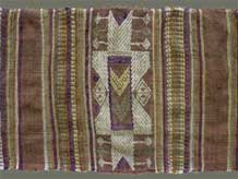 to Jpeg 63K From Xam Tai, detail of an unusual mosquito net border (now in the collection of Pamela Cross) which is a lovely shade of brown, with accents of purple, gold and yellow. It is unusual because of the design motifs: elongated, stylized star motifs with arrows; also present in a few places are stylized animal motifs and figures with up-raised hands. One end is a dark red rather than brown. It is all handspun cotton (or perhaps fine hemp?) with cotton and some silk supplementary weft. Condition is very good, tho there are soiled areas throughout. Size: 274" (22'-10") x 9.5"