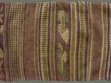 Jpeg 58K From Xam Tai, detail of an unusual mosquito net border (now in the collection of Pamela Cross) which is a lovely shade of brown, with accents of purple, gold and yellow. It is unusual because of the design motifs: elongated, stylized star motifs with arrows; also present in a few places are stylized animal motifs and figures with up-raised hands. One end is a dark red rather than brown. It is all handspun cotton (or perhaps fine hemp?) with cotton and some silk supplementary weft. Condition is very good, tho there are soiled areas throughout. Size: 274" (22'-10") x 9.5"