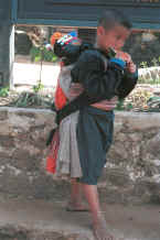 to Jpeg 29K Blue Hmong boy carrying a baby in a baby-carrier on his back in a village on Doi Suthep 8812l01
