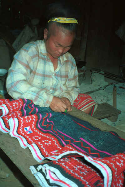 Blue Hmong woman drawing up a skirt into gathers in a village on Doi Chiang Dao on the road from Chiang Mai to Fang 8812n29