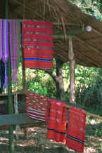to Jpeg 36K Hand woven koh (red) dyed handwoven sarongs with ikat dyed stripes hanging with a hand woven blouse and bands 8812p02.jpg