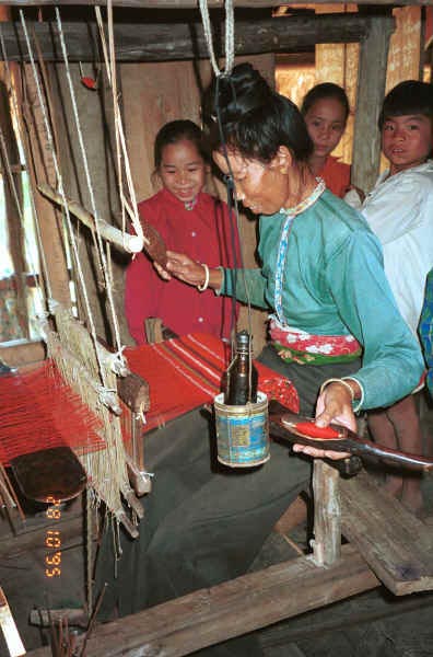 Jpeg 35K Black Thai woman, watched by her children, demonstrating weaving on a length of weaving for bags and bedding/cushion ends in a village near Dien Bien Phu, Lai Chau Province 9510D19.JPG