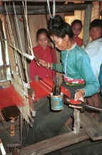 to Jpeg 35K Black Thai woman, watched by her children, demonstrating weaving on a length of weaving for bags and bedding/cushion ends in a village near Dien Bien Phu, Lai Chau Province 9510D19.JPG