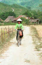 to Jpeg 41K Black Thai young woman cycling out of her village wearing a straw hat over her head dress to give added protection from the sun.  Dien Bien Phu, Lai Chau Province. 9510D36.JPG