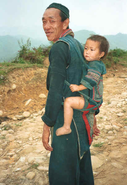 Jpeg 30K Black Hmong man with a young girl - probably his granddaughter - in a baby carrier on his back, in the hills around Sa Pa, Lao Cai Province.  9510I28.JPG