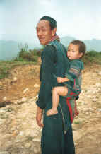 to Jpeg 30K Black Hmong man carrying his granddaughter on his back in a baby carrier in the hills around Sa pa, Northern Vietnam 9510I28