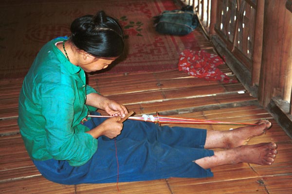 Jpeg 44K 9511A02 Weaving a braid with the warp tension achieved between toes and a tie around the waist. Although the braid is narrow quite a complicated shed is set up. Luong village on the road from Sa Pa to Lao Cai town, Lao Cai province.