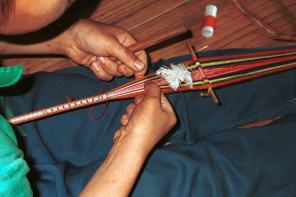 Jpeg 41K 9511A05 Weaving a braid with the warp tension achieved between toes and a tie around the waist. Although the braid is narrow quite a complicated shed is set up. Luong village on the road from Sa Pa to Lao Cai town, Lao Cai province.