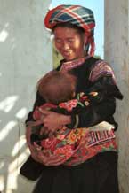 to Jpeg 53K 9510G27  Flowery Hmong mother with her baby outside a house in small road-side village near Phong Tho (Phong Thanh) in Lai Chau Province.