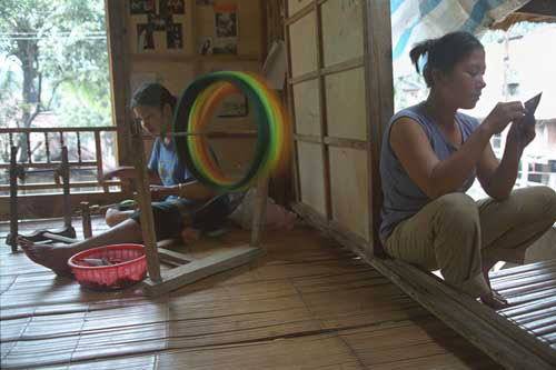 Jpeg 32K mc2 Kha Thi Thu spools factory-produced thread for use in weaving, while her sister-in-law embroiders a purse to sell to tourists. The Mai Chau valley, Hoa Binh Province, northern Viet Nam.