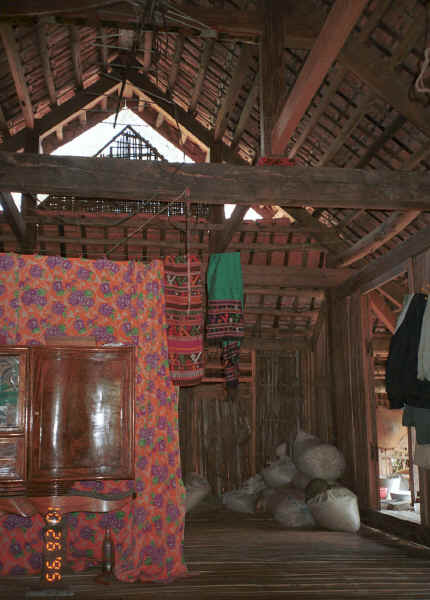 Inside a Southern White Thai house showing weavings by the lady of house including a head cloth which she is shown modeling below.  See the bags of cotton for spinning and weaving on the floor - Mai Chau District in Hoa Binh Province near the border with the north-western part of Thanh Hoa Province in north west Vietnam. 9510A23E