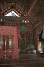to Jpeg 32K Inside a Southern White Thai house showing weavings by the lady of house including a head cloth which she is shown modeling below.  See the bags of cotton for spinning and weaving on the floor - Mai Chau District in Hoa Binh Province near the border with the north-western part of Thanh Hoa Province in north west Vietnam. 9510A23T